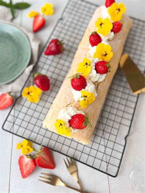 Biskuitrolle dekoriert mit Sahnetupfen und Erdbeeren