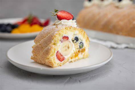 Biskuitrolle mit Frischkäsefüllung aufgeschnitten, Frucht und Puderzucker-Deko
