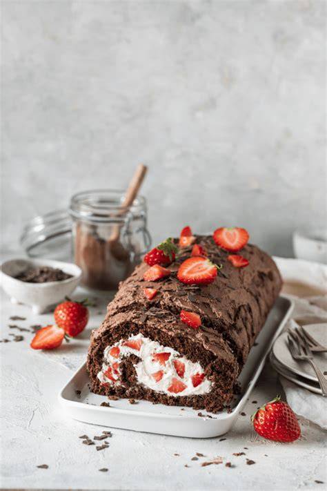 Biskuitrolle mit aufgeschnittenen Bananenscheiben und Cremefüllung auf einer Kuchenplatte