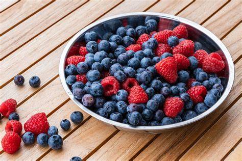 Blaubeeren und Himbeeren auf einem Holzbrett