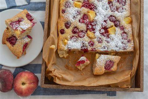 Blechkuchen angerichtet mit Staubzucker, Vanillesauce und Obst