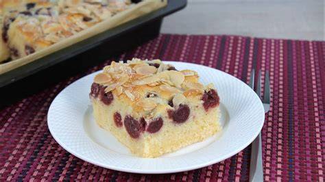Blechkuchen aufgeschnitten, Stücke mit Puderzucker, Vanilleeis und Sahne