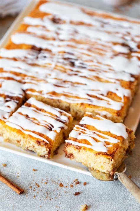 Blechkuchen mit Zimt und Sauerrahm aufgeschnitten, angerichtet auf einem Backblech