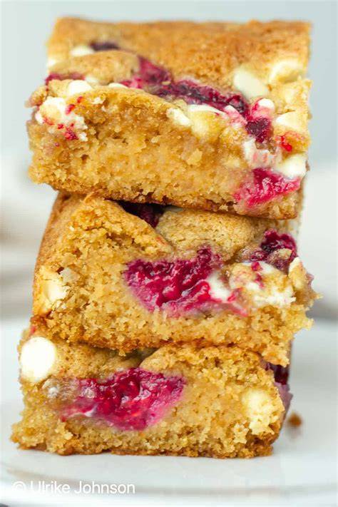 Blondies serviert auf Kaffeetisch, dekoriert mit weißer Schokolade und Beeren