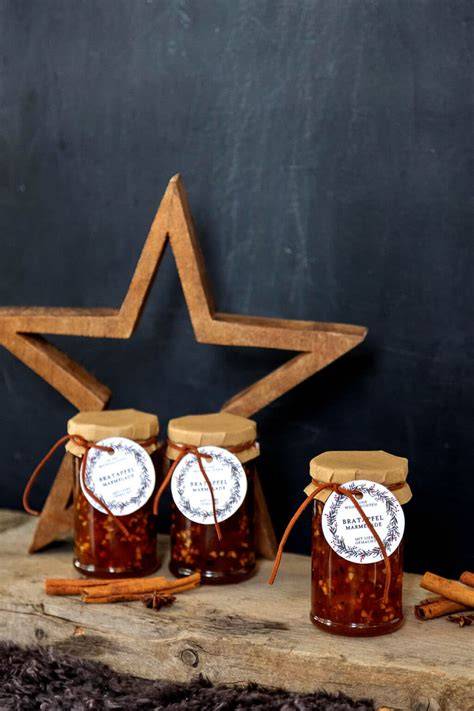 Bratapfel-Marmelade in dekorativen Gläsern mit Weihnachtsanhängern
