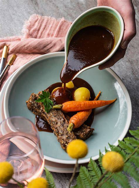 Bratensauce serviert zu Knödeln und Gemüse