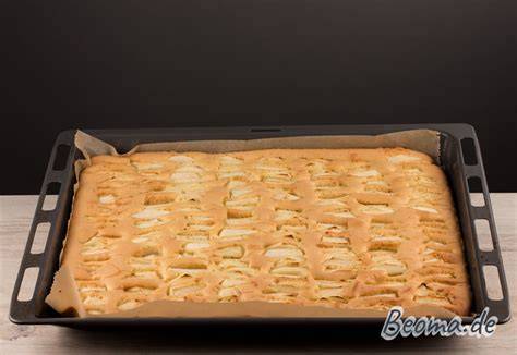 Bretonischer Apfelkuchen auf Backblech, Anschnitt zeigt fluffigen Teig und knusprige Mandeldecke