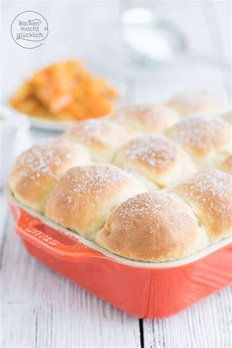 Buchteln vor dem Backen in der gefetteten Form, mit flüssiger Butter bestrichen