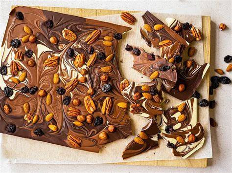 Bunte Bruchschokolade mit Trockenfrüchten und Nüssen, serviert auf einem Holzteller