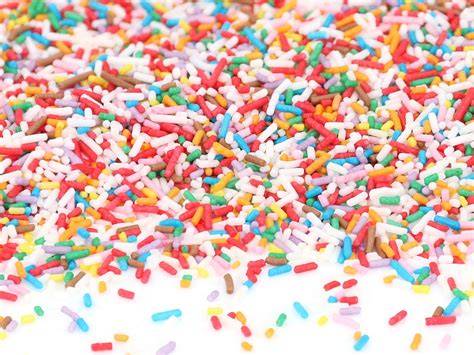 Bunte Zuckerstreusel und Kaubonbons auf pinker Glasur