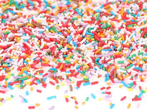 Bunte Zuckerstreusel und Schokolinsen auf Waffelbecher-Kuchen