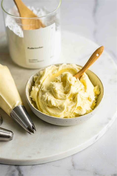 Buttercreme-Komposition: Schüssel mit geschlagener Buttercreme und Spritztüte