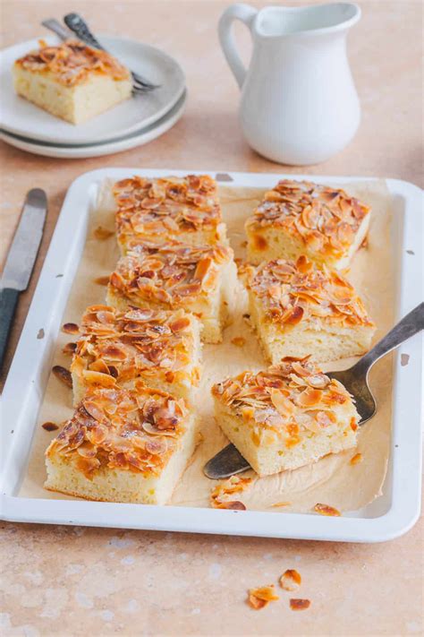 Buttermilchkuchen mit Mandeln auf dem Blech, angerichtet mit Mandelblättchen und Zitrone