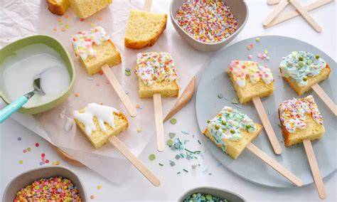 Cakesicles mit bunter Glasur und Streuseln auf Backpapier