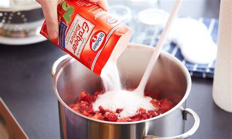 Campari-Flasche neben Kochtopf mit Marmelade
