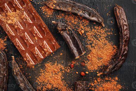 Chili-Flocken, Schoten und dunkle Schokolade auf Holzbrett