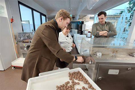 Chocolatier bei der Arbeit: Rosinen einstreuen und Tafeln veredeln