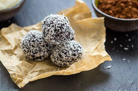 Chokladbollar in Kokosflocken auf Holzplatte