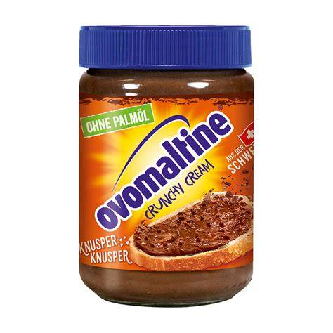 Cookie-Teigkugeln auf Backblech, daneben Glas Ovomaltine Crunchy Cream und Schokostreusel