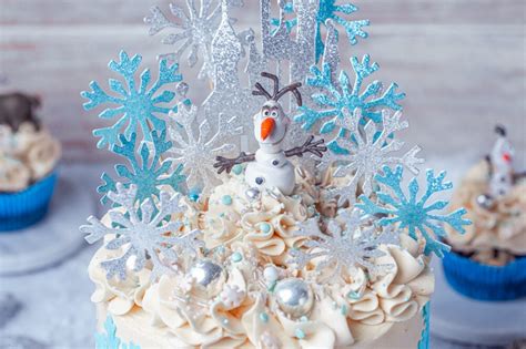 Cremehauben, Esspapier-Schneeflocken und Olaf-Figur als Caketopper auf weiß-blauer Torte