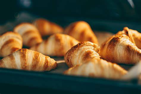 Croissants auf einem Backblech, angefeuchtet und im Ofen