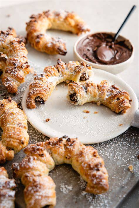 Croissants mit Nutella-Füllung und Zutaten auf einem Brett