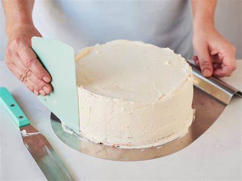 Das Glattstreichen einer Torte mit Teigkarte und Palette