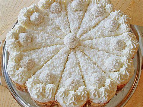 Dekoration einer Kokostorte mit Kokosraspeln und Raffaelo