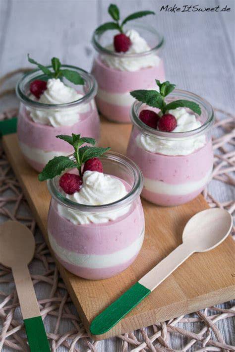Dekorierte Gläser mit Himbeeren, Sahne und Minze