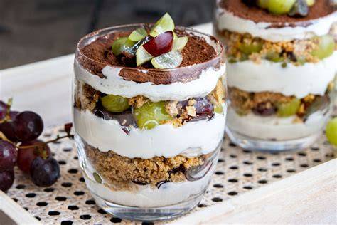 Dessert im Glas geschichtet mit Cookies und Weintrauben
