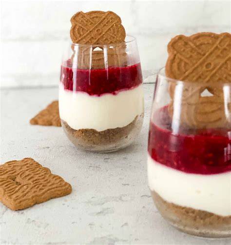 Dessertgläser mit Schichten aus Spekulatius, Creme und Himbeeren, dekoriert