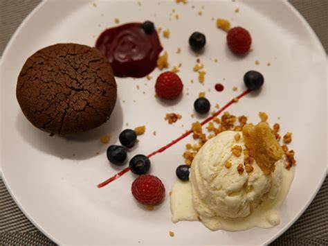 Dessertteller mit Schokokuchen, Eis, Himbeerspiegel und Beerenragout
