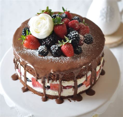 Detailfoto: Essbare Blüten, Beeren und Schokoladendekor auf weißer Torte