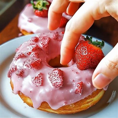 Donuts mit pinker Glasur auf Gitter, daneben Zutaten und frische Beeren
