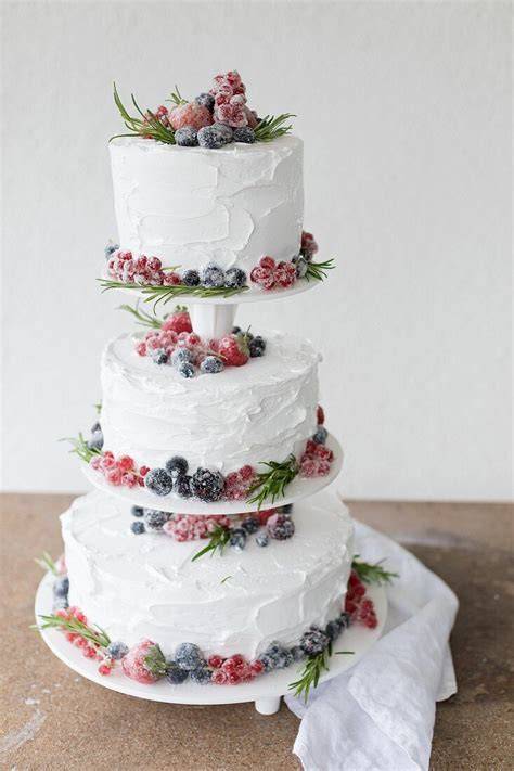 Dreistöckige Himbeer-Torte dekoriert mit Beeren und gezuckerten Rosenblättern
