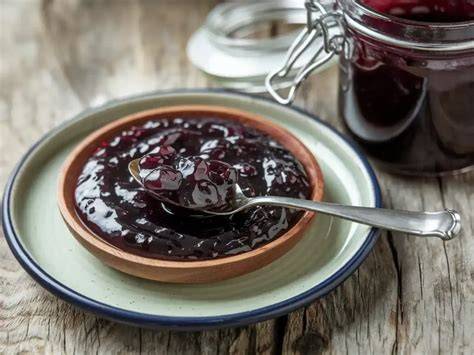 Ein Glas Kirsch-Cola-Marmelade auf einem Frühstückstisch