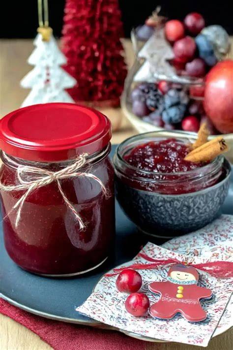 Ein Glas Weihnachtsmarmelade mit Beeren und Marzipan, dekoriert mit Zimtstange