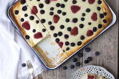 Ein sommerlicher Quarkkuchen auf einer Kuchentafel mit frischen Beeren dekoriert
