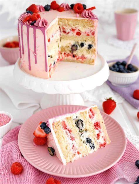 Eine kleine, frische Joghurt-Torte auf einem Tisch, garniert mit Beeren und Minze