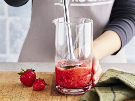 Einmachgläser und Pürierstab neben frischen Erdbeeren