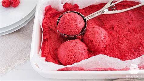 Eisförmchen mit Himbeereis im Gefrierfach und Rührvorgang