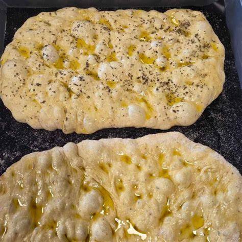 Ensaimadas auf einem Blech, mit Butter bestrichen und geriebenem Käse bestreut