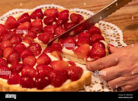 Erdbeer-Blechkuchen frisch angeschnitten auf einem rustikalen Holztisch
