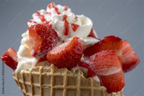 Erdbeereis in einer Waffel mit frischen Erdbeeren garniert