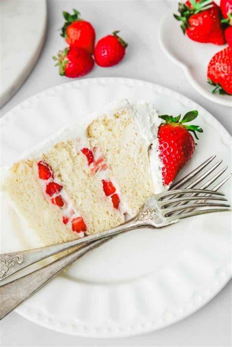 Erdbeertorte auf gedecktem Tisch, fertig angerichtet mit Sahne und frischen Erdbeeren