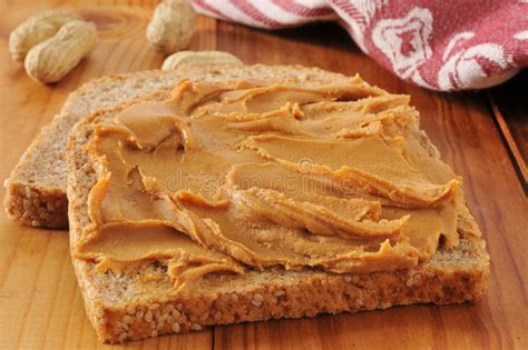 Erdnussbutter auf Löffel und Vollkornbrot
