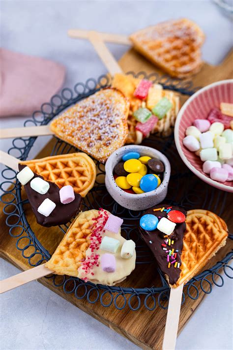 Eventmitarbeiter backen Waffeln am Stiel vor den Gästen