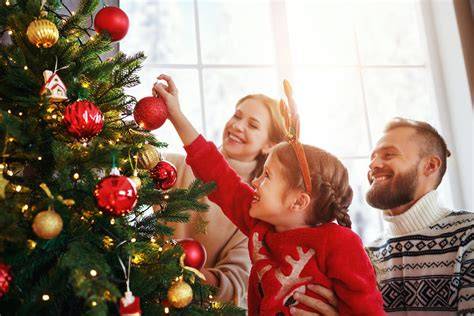 Familie schmückt gemeinsam den Christbaum mit Lebkuchen