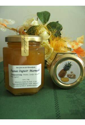 Fertig abgefüllte Ananas-Ingwer-Marmelade neben frischen Ananas und Ingwer