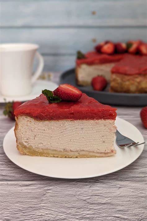 Fertig dekorierter Käsekuchen mit Erdbeer-Topping, umrahmt von Blüten